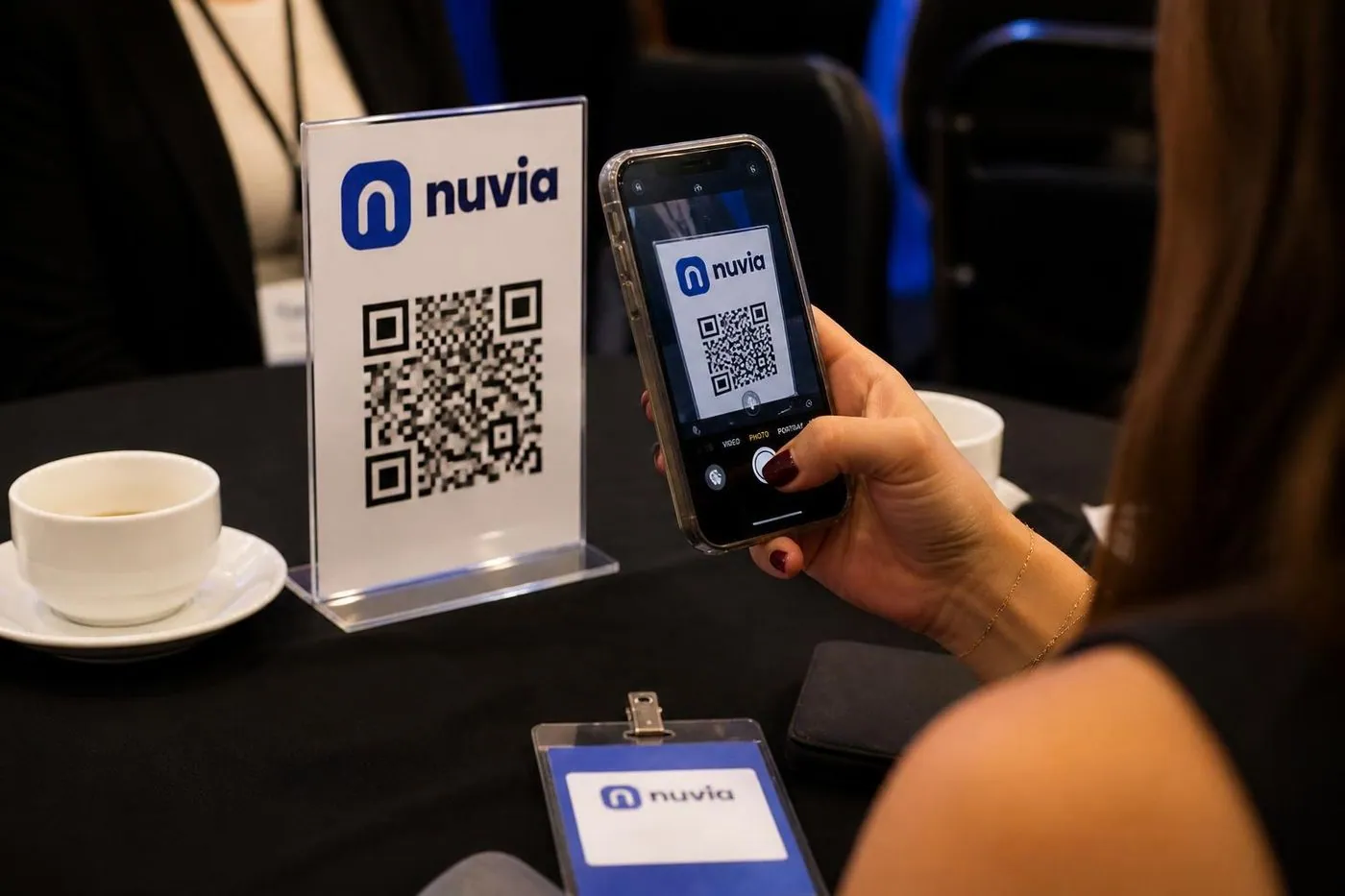 Convidada lendo o QR code de um display de mesa num almoço de convenção