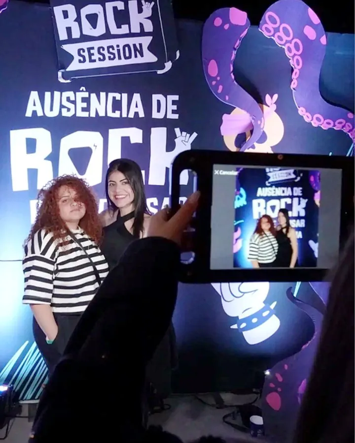 Fotógrafa do SelfiePop fotografando duas convidadas no painel do evento Rock Session