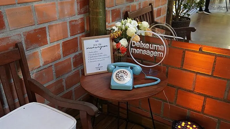 Telefone retrô azul numa mesa com parede de tijolos